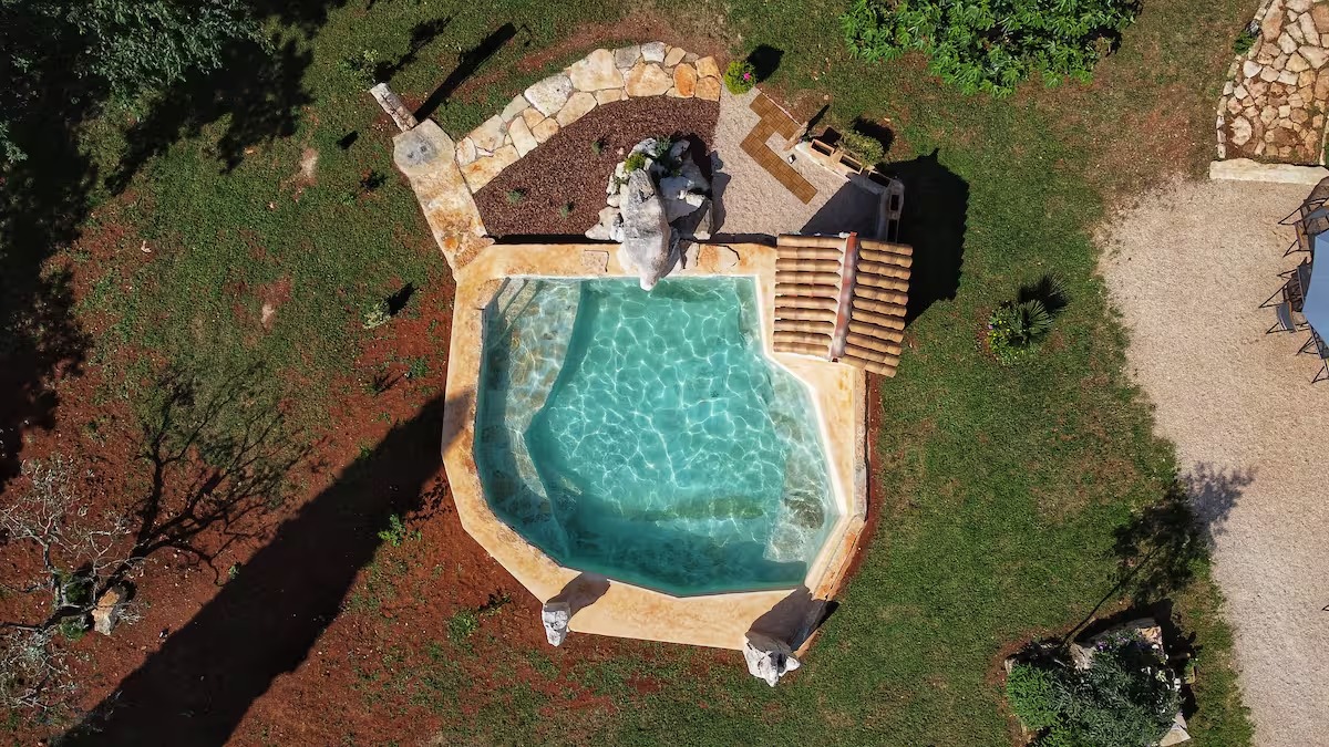 La piscina in pietra del Casale al Merlo vista dall'alto, immersa nel verde